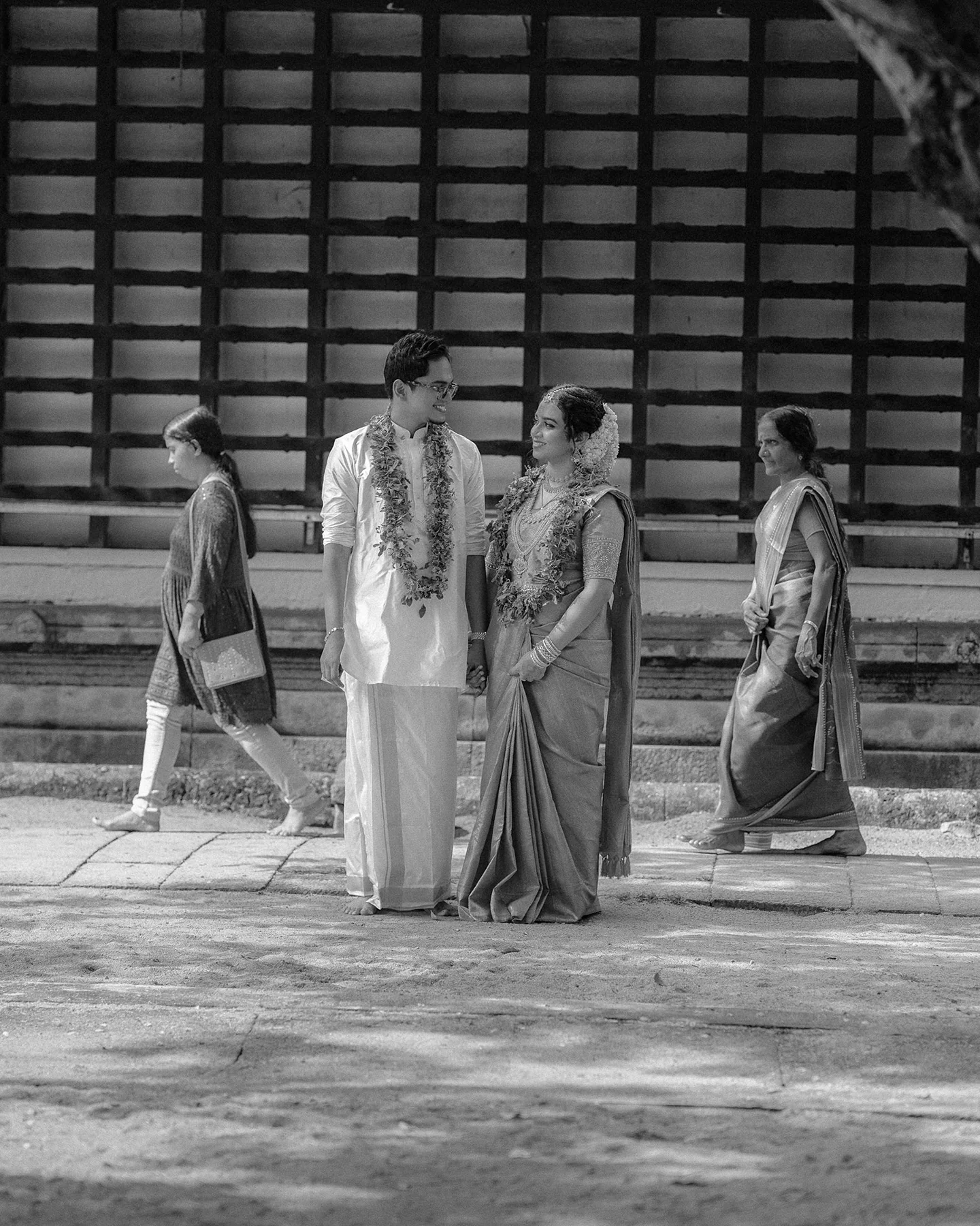 A newlywed couple sharing a quiet black-and-white moment outside a temple