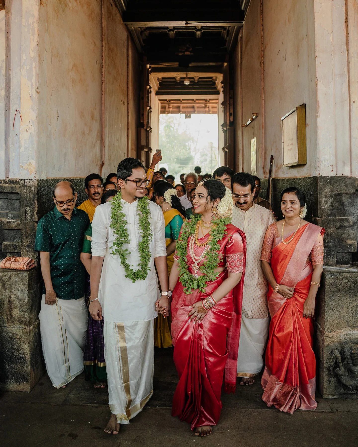 A newlywed couple leaving a temple hand in hand with their families